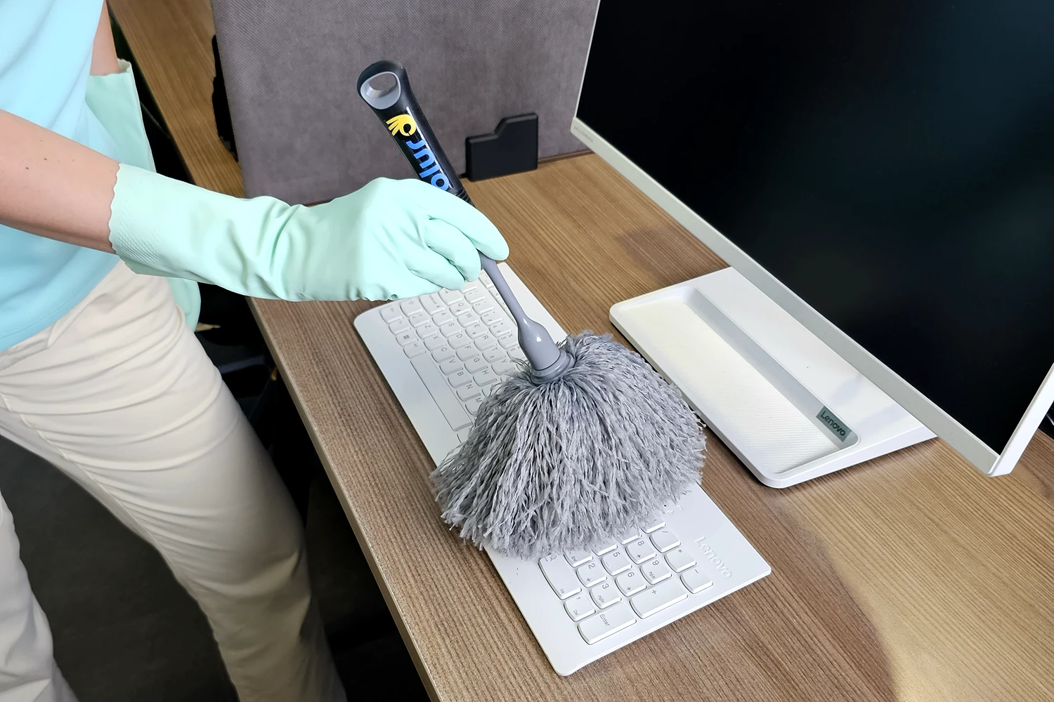 Ofis temizliğinde bilgisayar klavyesi, toz alma fırçası ile temizleniyor