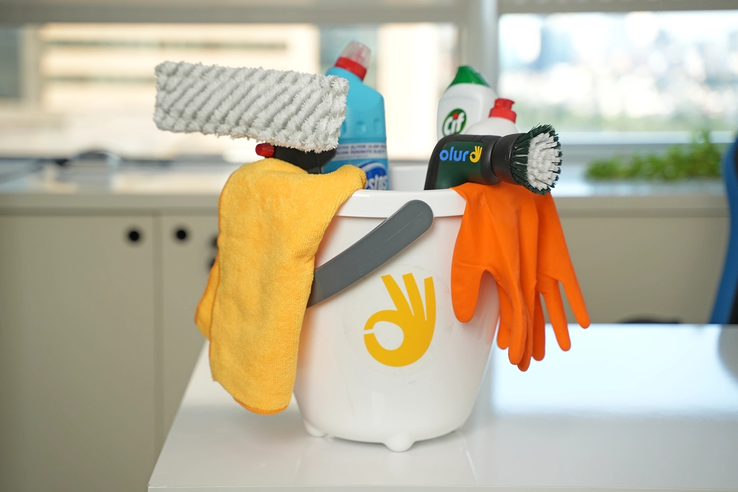 Ofis temizlik malzemeleri, kova içinde ve masa üzerinde duruyor